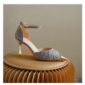 Detailed side view of a textured blue and gold pointed toe stiletto heel with ankle strap.