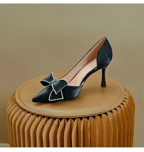 Dettaglio di scarpa d'Orsay in raso nero con decorazione a fiocco di strass.
