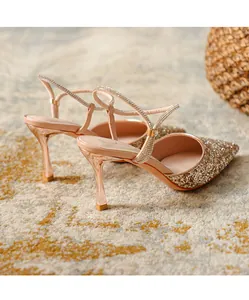 Detail view of elegant gold glitter high heels with rhinestone straps and slim heels.