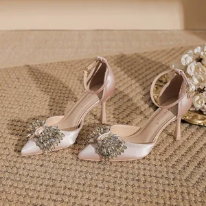 Elegant pink satin pointed-toe stilettos with sparkling rhinestone bow and ankle strap.