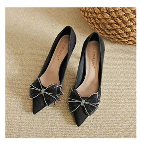 Detailed view of elegant black pointed-toe heels with a rhinestone-edged bow decoration