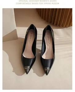 Macro view of black pointed-toe patent leather high heels with luxury metal buckle