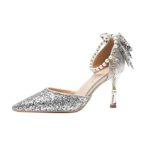 Silver sequined bridal high heels with pearl strap and bow detail on white background.