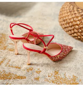 Detailed view of red glitter pointed toe pumps with rhinestone straps and slim heels.