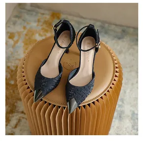 Detail of black satin pointed toe heels with metallic tip and ankle strap
