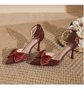 Nahaufnahme eines weinroten High Heels mit einer edlen Seidenschleife und goldener Schnalle