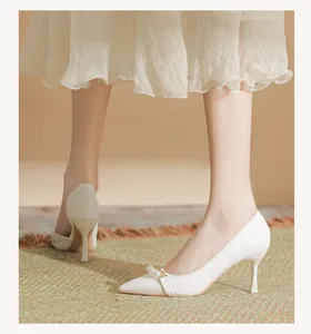Detailed side view of white pointed toe high heels with elegant pearl strap embellishment