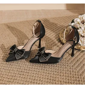 Nahaufnahme von eleganten schwarzen High Heels mit Schleife und Kettenbesatz