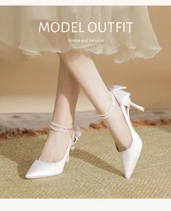 Elegant white satin wedding pumps featuring pearl ankle straps and bow detail on model