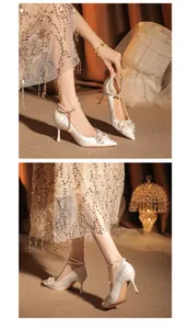Vista detallada de elegantes tacones de aguja blancos para novia con perlas y flores