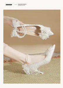 Detailed macro view of pearl ankle strap and lace embroidery on white bridal heels