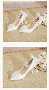Detail view of elegant white lace bridal heels decorated with pearls and chic bows
