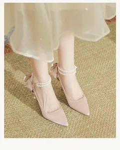 Close-up of elegant pink satin pointed-toe heels featuring pearl ankle straps and bow
