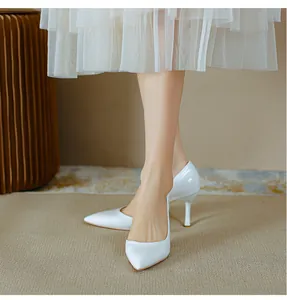 Gros plan d'escarpins en cuir verni blanc à bout pointu portés par un mannequin