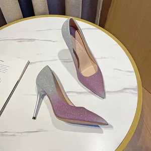 Elegante Glitzer-Stilettos mit Farbverlauf in Lila und spitzer Zehenpartie auf einem Marmortisch