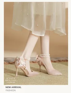 Elegant champagne satin pointed-toe heels featuring a silk bow and pearl ankle strap