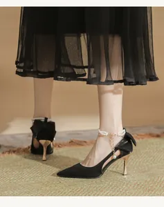 Close-up of black pointed stiletto heels featuring elegant pearl strap and bow