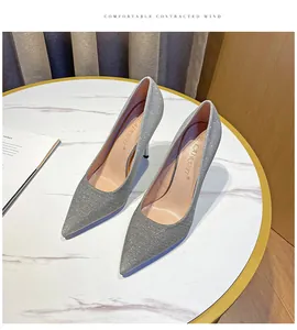 Detailansicht eleganter silberner Glitzer-Stilettos mit spitzer Zehenpartie auf Marmortisch.