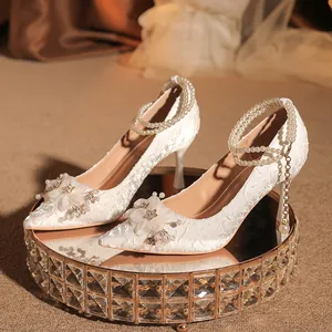 Elegantes zapatos de novia blancos con tacón de aguja y detalles de perlas