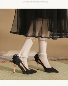Elegant black high heel shoes featuring oversized bow and pearl ankle strap detail