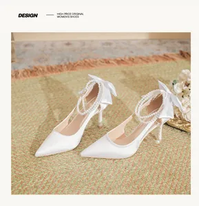 Elegant white pointed-toe bridal heels featuring a pearl ankle strap and silk bow.