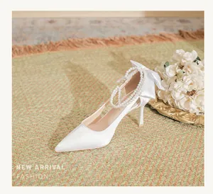Elegant white satin wedding high heels featuring a pearl ankle strap and a satin bow detail