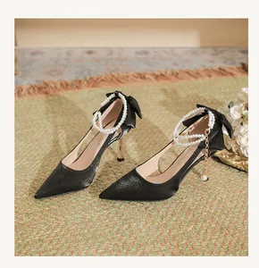 Elegant pointed black stiletto heels featuring pearl ankle straps and back bow details