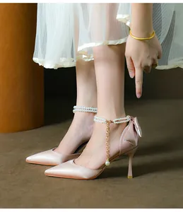 Close-up of pink satin stiletto pumps featuring a heel bow and elegant pearl strap