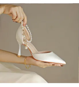 Detailansicht eines elfenbeinfarbenen Pumps mit elegantem Perlenknöchelriemen
