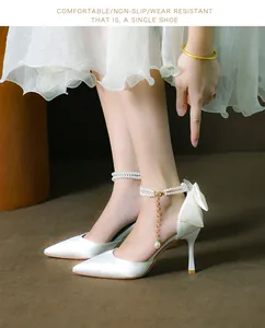 Elegant white pointed-toe stiletto pumps with delicate pearl ankle strap and rear bow detail