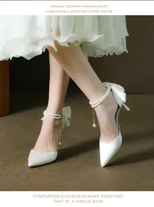 Elegant white stiletto heels with pearl ankle straps and silk bow details.