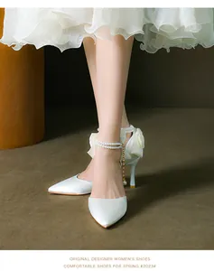 Detail view of white satin pointed-toe stilettos with elegant bow and pearl strap