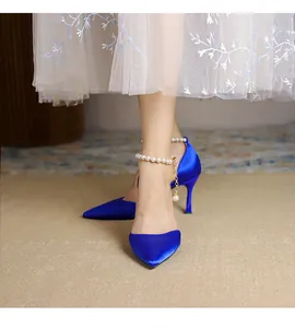 Nahaufnahme von blauen Satin-Stilettos mit spitzer Zehenpartie und elegantem Perlen-Fesselriemen