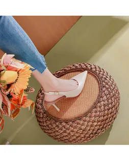 Λεπτομέρεια μπεζ μυτερές γόβες slingback φορεμένες από μοντέλο σε υφαντό σκαμπό