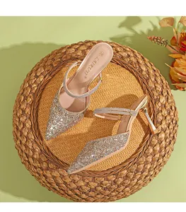 Elegante primo piano di sandali mule glitterati con tacco alto e punta su stuoia