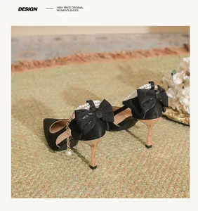 Detailed view of black bridal heels with pearl straps and decorative bows