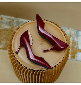 Vue détaillée d'escarpins en cuir verni rouge vin à bout pointu sur un tabouret beige