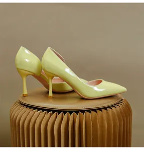 Gros plan d'escarpins d'Orsay en cuir verni brillant vert citron sur un tabouret