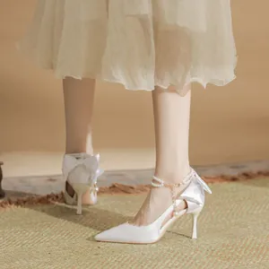 Elegant white wedding high heels with pearl ankle straps and bow detail.
