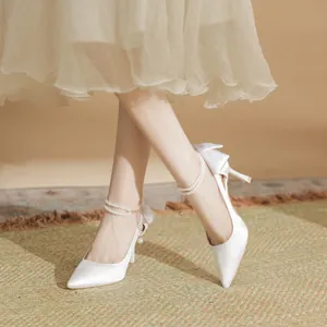 Elegant white bridal high heels with pearl ankle strap and bow detail for weddings.
