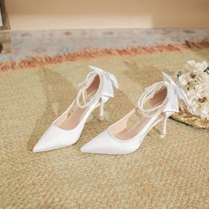 Elegant white satin wedding high heels with pearl ankle straps and bow detail.