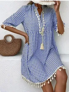 Detailed view of the geometric blue print and white tassel trim on a bohemian dress