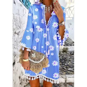 Détail d'une robe d'été bleu clair à imprimé marguerites avec bordure à pompons