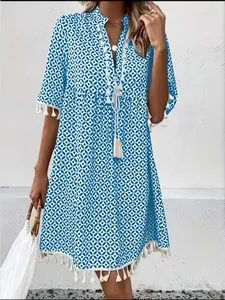 Detail view of blue geometric print bohemian dress with tassel hem and V-neckline