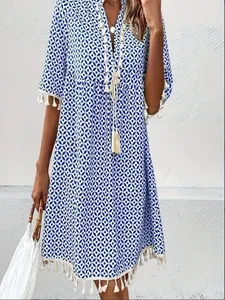 Detailed view of a bohemian blue and white geometric print summer dress with tassel hem