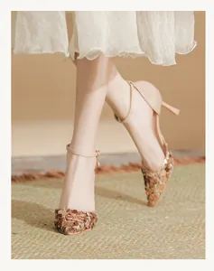 Detailed view of elegant pointed toe sandals with large sequins and ankle strap worn by a model