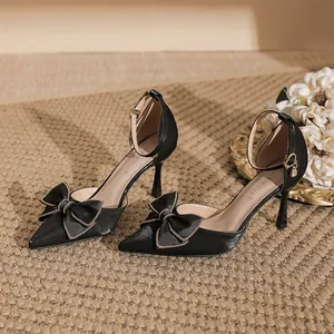 Elegante schwarze Stilettos mit spitzer Zehenpartie und schicker Schleife mit Goldkette