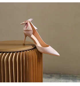 Primo piano di décolleté in raso rosa con un elegante fiocco sul retro del tacco a spillo.