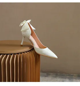 Dettaglio laterale di una scarpa in raso bianco con tacco alto e fiocco decorativo