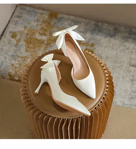 Dettaglio di scarpe décolleté in raso bianco a punta con elegante fiocco sul retro